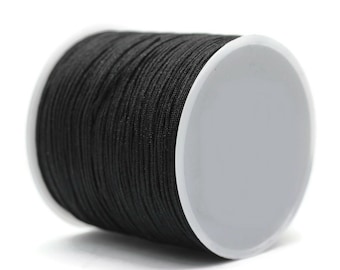 May include: A spool of black elastic cord, wound around a white plastic bobbin.