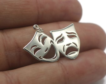 Puede incluir: Encanto de plata con dos máscaras de teatro, una sonriente y otra frunciendo el ceño. Las máscaras están conectadas en la parte superior y tienen un diseño detallado.