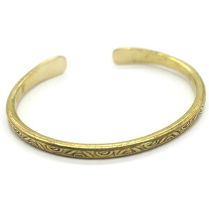 May include: A gold-toned bangle bracelet with a decorative etched design.