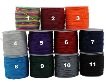 May include: Eleven spools of colorful elastic cord, numbered 1 through 11. The cords are arranged in a pyramid shape, with the top spool being rainbow colored and the bottom spool being black.