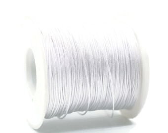 May include: A spool of white cord, tightly wound around a white plastic core. The cord appears smooth and is suitable for various crafting and jewelry-making projects. The image is set against a bright white background.