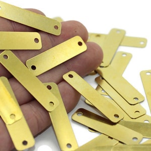 Puede incluir: Un montón de pequeñas etiquetas rectangulares de latón con dos agujeros en cada una. Las etiquetas son de color dorado brillante y son perfectas para agregar un toque personalizado a las manualidades y los proyectos.