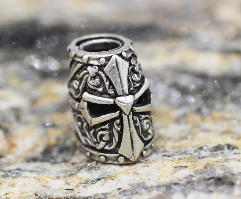 May include: Silver charm with a detailed design of a knight's helmet with a cross on the front.