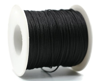 May include: A spool of black waxed cord, a type of string used for crafts and jewelry making.