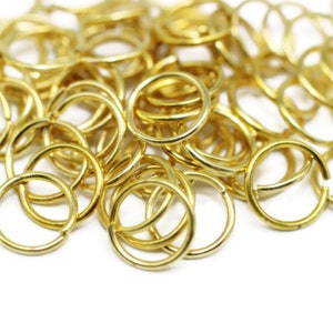 May include: A pile of gold-colored metal jump rings. The rings are small and round, and they are all linked together.