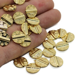 May include: A collection of gold-toned metal beads with a textured surface and a raised line across the center. The beads are round and have a hole in the center for stringing.