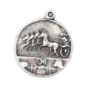 May include: Silver charm featuring a detailed relief of a chariot pulled by four horses. The chariot driver is visible in the background. The charm is round and has a loop at the top for attaching to a necklace or bracelet.