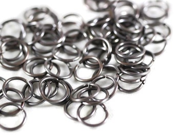 May include: A pile of silver jump rings, a type of metal ring used in jewelry making.
