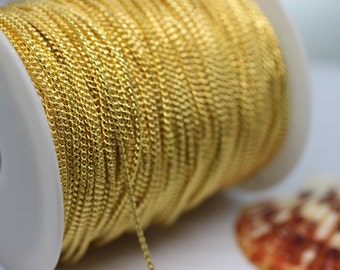 May include: A spool of gold-colored chain, wound tightly around a white plastic spool. The chain is a delicate, twisted design.