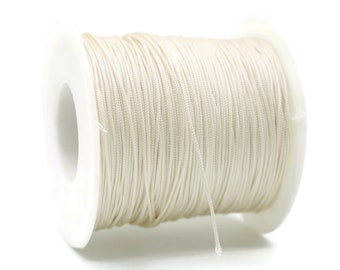 May include: A spool of white waxed cord, a type of string used for crafts and jewelry making.