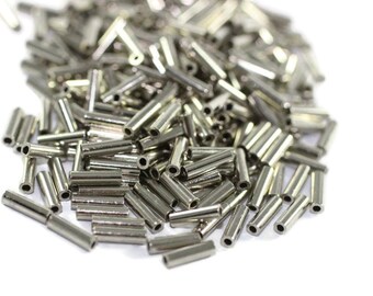 May include: A pile of silver metal tubes, likely used for jewelry making or crafts.