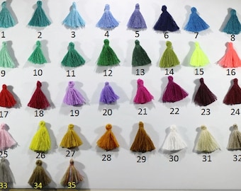 May include: A collection of 35 colorful tassels, each with a unique hue. The tassels are arranged in rows, numbered from 1 to 35, showcasing a wide spectrum of colors, including teal, blue, purple, green, pink, yellow, orange, and brown.
