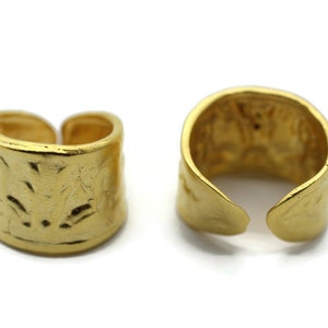 May include: Two gold-toned metal rings with a textured surface. The rings are open and can be adjusted to fit different finger sizes.