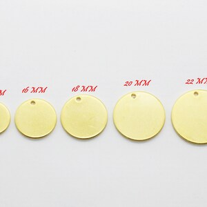 May include: A collection of brass-colored, round metal tags in various sizes, ranging from 10 mm to 25 mm in diameter. Each tag has a small hole at the top for attaching to a chain or other material. The tags are displayed on a white surface.
