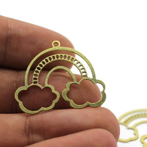 Könnte beinhalten: Goldfarbener Metall-Regenbogen-Anhänger mit Wolken-Design. Der Anhänger hat oben ein Loch zum Anbringen an Schmuck oder andere Bastelarbeiten.