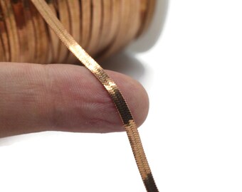 May include: A close-up of a gold-toned snake chain, showing the individual links and the shiny finish.