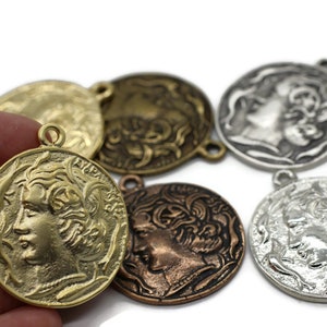 May include: Assortment of five antique-style metal medallions with a profile of a woman's face on each. The medallions are in various shades of gold, silver, and copper.