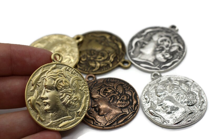 May include: Assortment of five antique-style metal medallions with a profile of a woman's face on each. The medallions are in various shades of gold, silver, and copper.