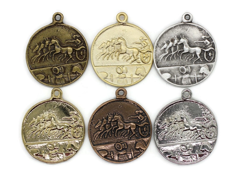 May include: Six round metal charms with a design of a chariot pulled by four horses. The charms are in different finishes: gold, silver, bronze, and antique silver.