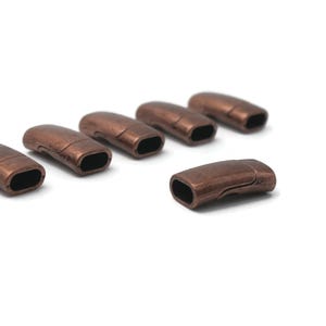 May include: Six antique copper-toned magnetic clasps for jewellery making. The clasps are in a row, with one clasp slightly offset from the others.