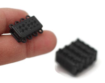 May include: Black plastic magnetic clasps for jewellery making. The clasps have a diamond pattern and four loops.