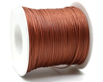 May include: A spool of brown waxed cord, wound tightly on a white plastic bobbin.