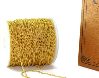 May include: A spool of gold-colored chain, wound around a white plastic spool. The chain is a fine, delicate style.