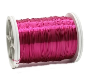 Könnte beinhalten: Eine Spule mit leuchtend pinkfarbenem Metalldraht, auf einer weißen Kunststoffspule gewickelt.