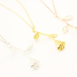 May include: Three gold rose necklaces with different colored finishes: silver, gold, and rose gold. The rose pendants are detailed and realistic.