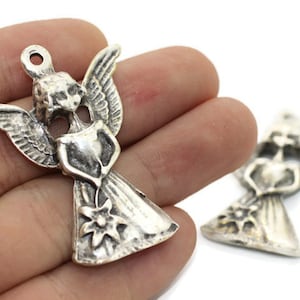 May include: Two silver angel charms with wings, a heart, and a flower. The angel charms are holding a heart in their hands and have a flower on their dress.