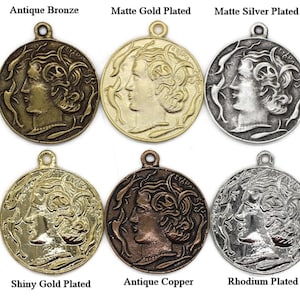 May include: Six round metal charms with a profile of a woman's face on each. The charms are in different finishes: antique bronze, matte gold plated, matte silver plated, shiny gold plated, antique copper, and rhodium plated.