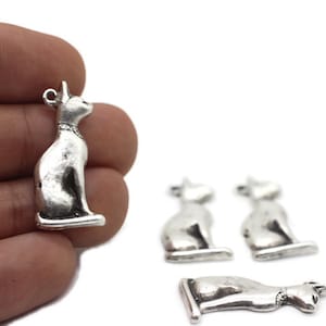 Puede incluir: Cuatro abalorios de plata con forma de gato, cada uno con un diseño detallado. Los abalorios son perfectos para hacer joyas o para añadir un toque de fantasía a las manualidades.