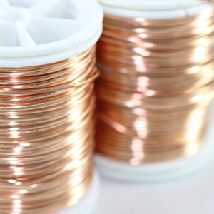 Peut inclure: Deux bobines de fil de cuivre, chacune enroulée autour d'une bobine en plastique blanc. Le fil est de couleur cuivre brillant et chaud.