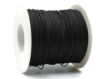 May include: A spool of black elastic cord, wound around a white plastic bobbin.