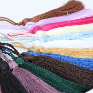 Puede incluir: Surtido de borlas de colores en varios colores, incluyendo marrón, rosa, rojo, blanco, azul, dorado, azul oscuro, marrón, verde, morado y negro. Las borlas están hechas de hilos suaves y sedosos y son perfectas para agregar un toque de elegancia a cualquier proyecto.