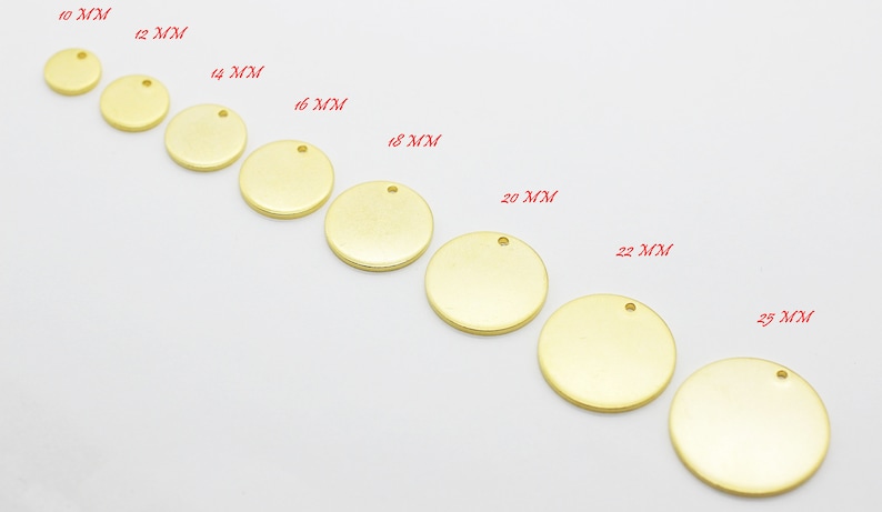 May include: A collection of gold-colored, round metal blanks for jewelry making, ranging in size from 10mm to 25mm. Each disc has a small hole for attaching to chains or other components. The sizes are labeled in red text.