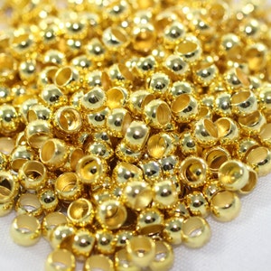May include: A large pile of gold-colored metal beads. The beads are round with a small hole in the center. They are perfect for jewelry making or other craft projects.
