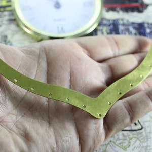 以下が含まれることがあります： 湾曲した形と複数の穴のある真鍮色の金属片。この作品はクラフトやジュエリー作りに適しています。