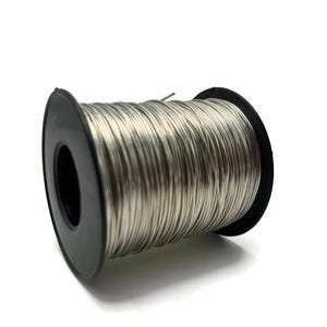 May include: A spool of silver-colored wire. The wire is tightly wound around a black plastic spool. The image is taken against a white background, highlighting the metallic sheen of the wire. This item is suitable for jewelry making and crafts.