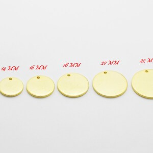 May include: A collection of gold-colored, round metal blanks in various sizes, ranging from 10 mm to 25 mm. Each blank has a small hole at the top for attaching to jewelry or other crafts. The sizes are labeled in red text.
