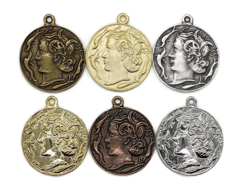 May include: Six antique-style gold, silver, and bronze pendants featuring a profile of a woman's face with flowing hair. Each pendant has a loop at the top for hanging.