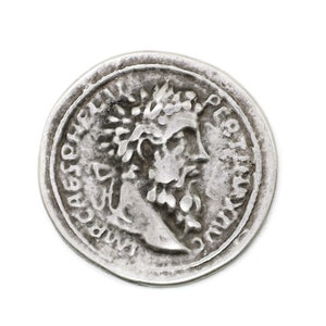 Puede incluir: Una moneda de plata con el retrato de un hombre con corona y barba. La inscripción alrededor del retrato dice "IMP CAESAR AVG F.
