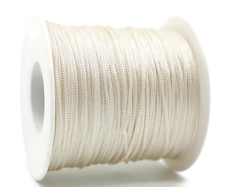 May include: A spool of off-white waxed cord, wound tightly on a white plastic bobbin.