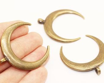 May include: Three gold-toned crescent moon charms with a smooth, slightly textured finish. Each charm has a small loop at the top for attaching to jewelry or other crafts.