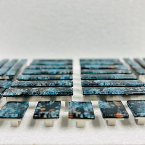 May include: A collection of blue and black glass cabinet knobs with silver metal bases. The knobs have a speckled pattern.