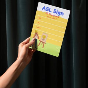 Puede incluir: Un letrero rectangular con el texto "ASL Sign" en azul y "ASL Study Group" en rojo. El letrero tiene un fondo amarillo con líneas para la fecha, la hora y el lugar. También hay una ilustración de dibujos animados de una persona que firma y un pequeño caballete con la palabra "Laugh".