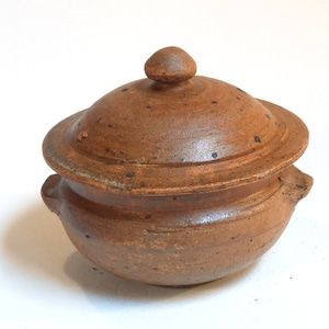May include: A brown ceramic pot with a lid and a knob on top. The pot has a speckled glaze and is handmade.