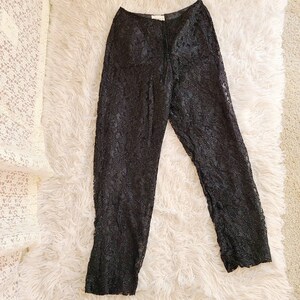 May include: Black lace pants with a drawstring waist. The pants are made of a sheer fabric and have a floral pattern.