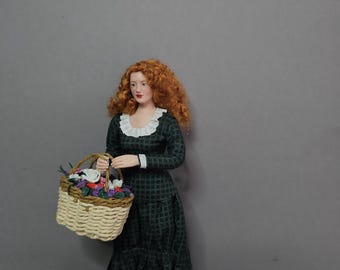May include: A miniature doll with curly red hair wearing a long-sleeved dark green dress with a black grid pattern and a white ruffled collar. The doll holds a woven light tan basket filled with small colorful flowers and wears white shoes.