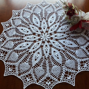 May include: A white crocheted doily with a delicate floral pattern. The doily is circular and has a scalloped edge.